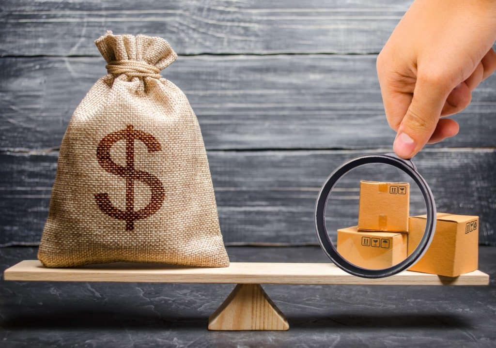 Gangorra com um saco com um símbolo do cifrão de um lado e do outro 3 caixas de papelão e uma lupa.