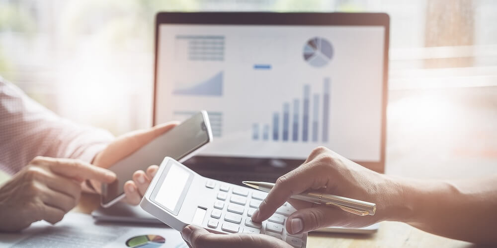 duas pessoas realizando cálculos na calculadora sobre o pagamento de tributação para provedores de internet