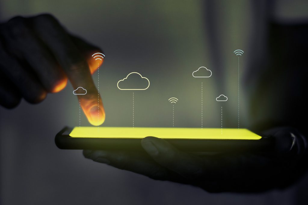 Pessoa segurando um dispositivo móvel com um holograma saindo da tela com ícones de internet, representando o serviço de um provedor de acesso à internet.