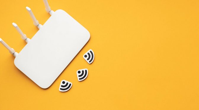 sistema-mikweb Roteador branco em fundo amarelo com símbolos de Wi-Fi, representando o resultado do provisionamento do sistema MikWeb.