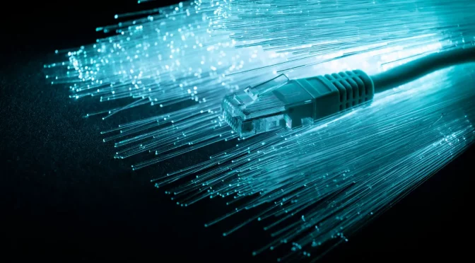Cabo de internet sobre vários filamentos iluminados, ilustrando a parte interna da fibra óptica.