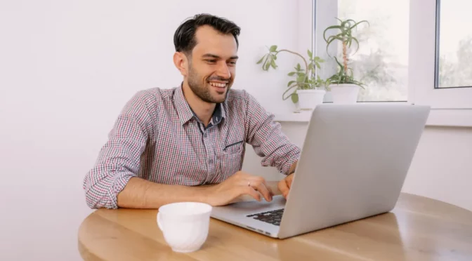 Homem trabalhando em seu notebook feliz com o provedor de internet local que contratou