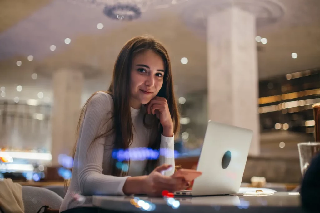 Mulher sorrindo utilizando um computador e um celular representando o cabo low friction