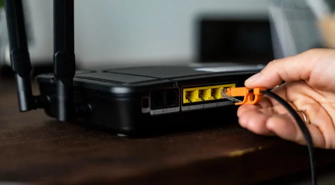 Homem plugando cabo de rede em seu roteador após descobrir como configurar seu roteador wifi